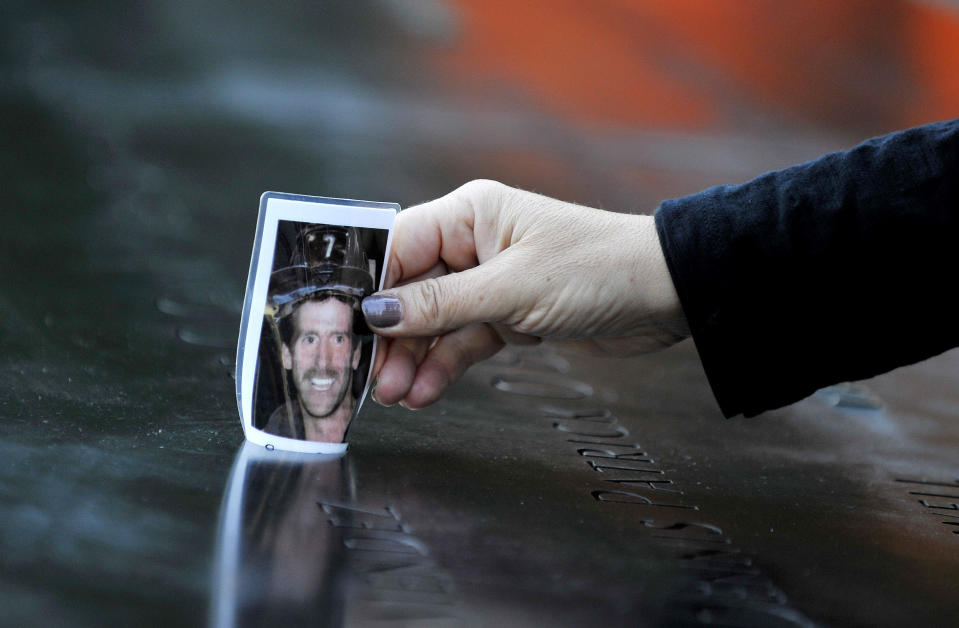 Christine Gonda pone una foto del bombero George Kane, en el lugar donde su nombre se encuentra gravado, en la piscina Sur, durante una ceremonia en honor a los fallecidos del 11 de septiembre de 2001, en el World Trade Center, este 11 de septiembre de 2012, en Nueva York. Justin Lane-Pool/Getty Images