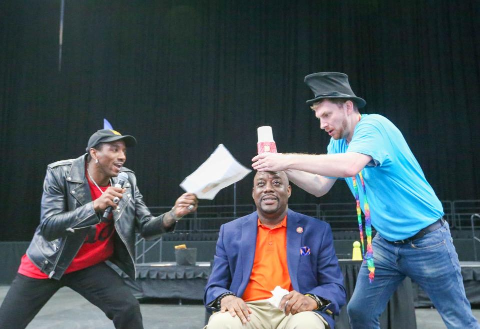 Former University of Georgia and New England Patriots wide receiver Malcolm Mitchell and a magician perform a trick with Savannah Mayor Van Johnson on Tuesday, October 17, 2023 during a Reading Rally at Enmarket Arena.