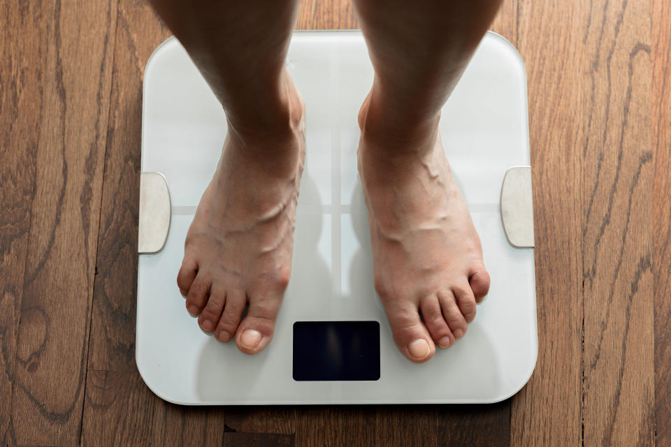 Feet standing on a white bathroom scale