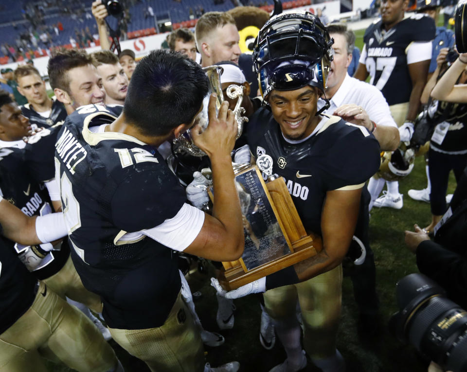 Colorado quarterback Steven Montez, left, kisses the Rocky Mountain Showdown Trophy as wide receiver Shay Fields holds the cup after defeating Colorado State in an NCAA college football game Friday, Sept. 1, 2017, in Denver. (AP Photo/David Zalubowski)