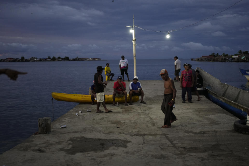 Hombres se reúnen en un muelle en la isla Gardi Sugdub, parte del archipiélago de San Blas frente a la costa caribeña de Panamá, el sábado 25 de mayo de 2024. Debido al aumento del nivel del mar, unas 300 familias indígenas Guna se trasladarán a nuevas casas construidas por el gobierno en tierra firme. (Foto AP/Matías Delacroix)