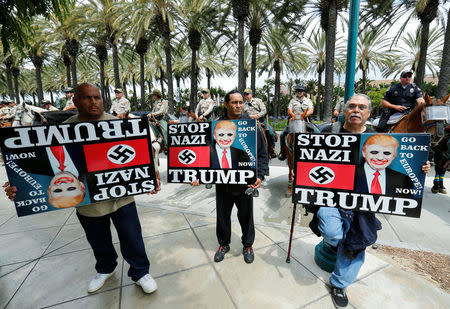 Three anti-Trump demonstrators protest as Orange County Sheriff officers stand watch outdoors before Republican U.S. Presidential candidate Donald Trump speaks at a campaign event in Anaheim, California U.S. May 25, 2016. REUTERS/Mike Blake