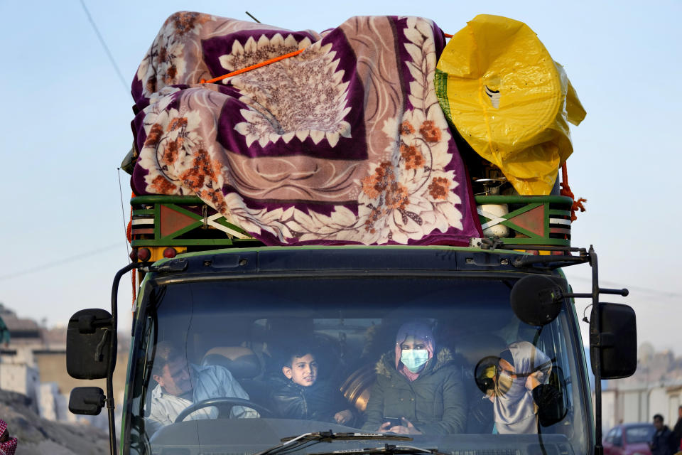 Syrian refugee family sit inside a truck which carry their belongings, as they wait at a gathering point to cross the border back home to Syria, in the eastern Lebanese border town of Arsal, Lebanon, Wednesday, Oct. 26, 2022. Several hundred Syrian refugees boarded a convoy of trucks laden with mattresses, water and fuel tanks, bicycles – and, in one case, a goat – Wednesday morning in the remote Lebanese mountain town of Arsal in preparation to return back across the nearby border.(AP Photo/Hussein Malla)