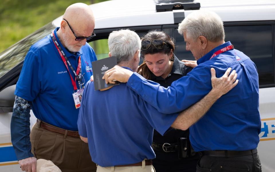 A Nashville police officer joins others in prayer outside the school on Tuesday - JAMES BREEDEN