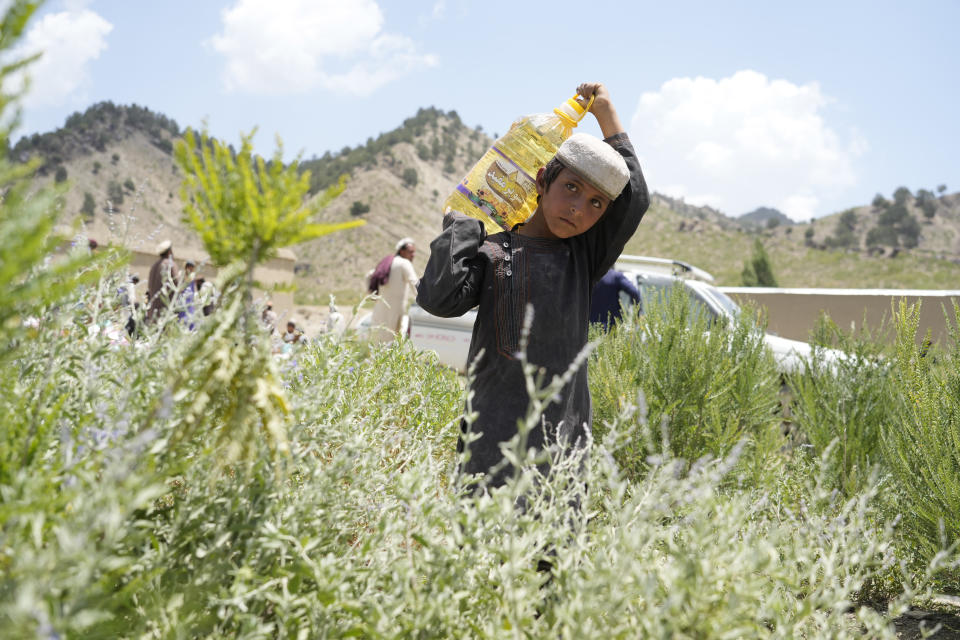 Afghan boy carries carries donated oil at a camp after an earthquake in Gayan district in Paktika province, Afghanistan, Sunday, June 26, 2022. A powerful earthquake struck a rugged, mountainous region of eastern Afghanistan early Wednesday, flattening stone and mud-brick homes in the country's deadliest quake in two decades, the state-run news agency reported. (AP Photo/Ebrahim Nooroozi)