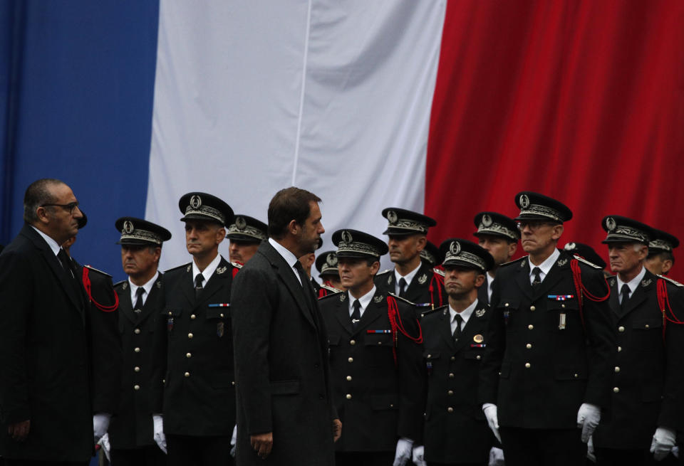 French Interior Minister Christophe Castaner, center, and Junior Minister Laurent Nunez, left, walk past police officers in the courtyard of the Paris police headquarters during a ceremony for the four victims of last week's knife attack, Tuesday, Oct. 8, 2019 in Paris. France's presidency says the four victims of last week's knife attack at the Paris police headquarters will be posthumously given France's highest award, the Legion of Honor. (AP Photo/Francois Mori)