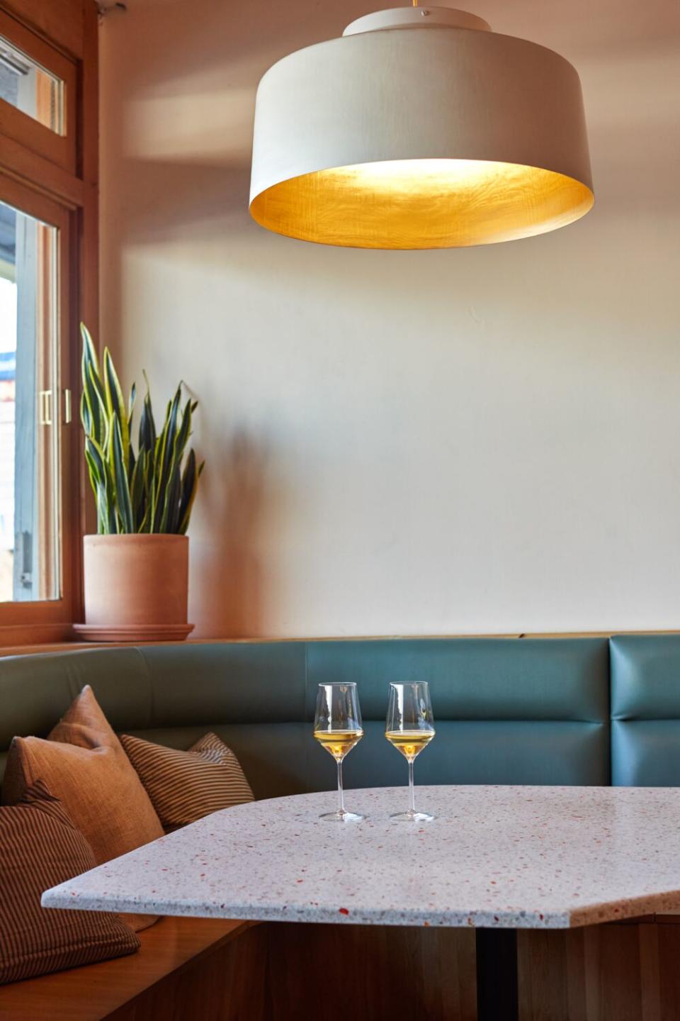 Two glasses of wine on a table with turquoise banquette seating.