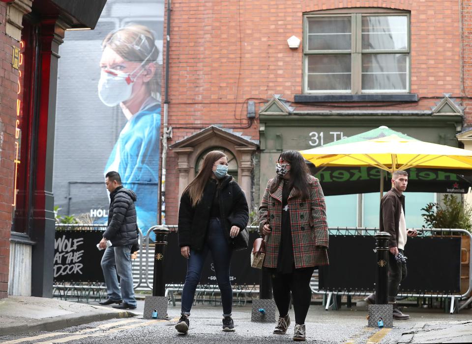 People wearing a face mask walk near a mural of a nurse in the Northern Quarter of ManchesterPA