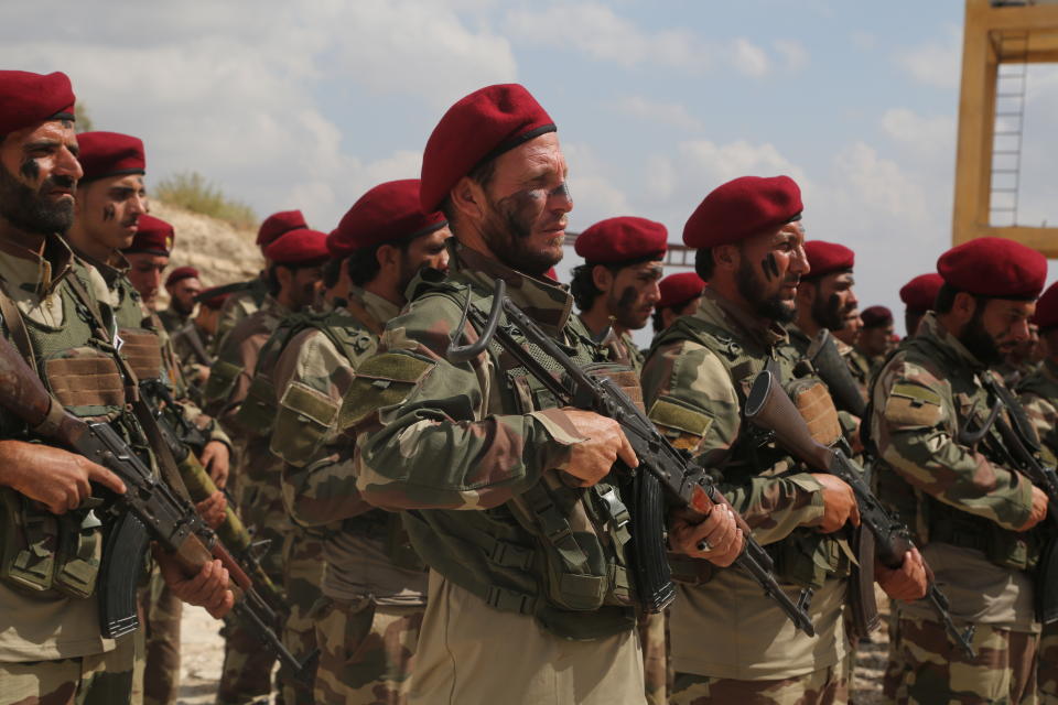 FILE - In this Monday Oct. 7, 2019 file photo, Turkish-backed forces from the Free Syrian Army, stand in formation during military maneuvers in preparation for a Turkish incursion targeting Syrian Kurdish fighters, near Azaz town, north Syria. The Turkish trained and funded Syrian forces present themselves as heirs to the uprising against President Bashar Assad. But while they include some Islamist and former rebel factions, a large number are Arab and Turkmen fighters from northern and eastern Syria with an ax to grind against the Kurds and a reputation for violence and looting. (AP Photo, File)