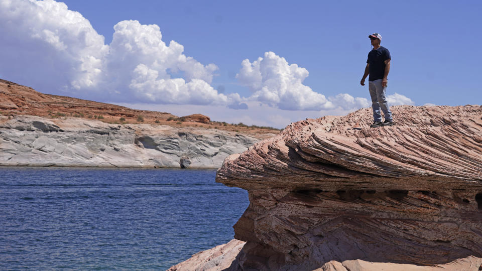 FILE - Bill Schneider stands near Antelope Point's public launch ramp on Lake Powell on July 31, 2021, near Page, Ariz., after water levels hit a historic low amid a climate change-fueled megadrought engulfing the U.S. West. Federal water officials have announced that they will keep hundreds of billions of gallons of Colorado River water inside Lake Powell instead of letting it flow downstream to southwestern states and Mexico. U.S. Assistant Secretary of Water and Science Tanya Trujillo said Tuesday, May 3, 2022, that the move would allow the Glen Canyon Dam to continue producing hydropower while officials strategize how to operate the dam with a lower water elevation. (AP Photo/Rick Bowmer, File)