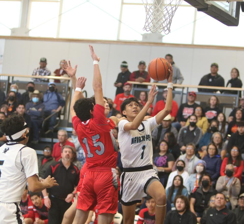 Navajo Prep's  Xavier Nez (1) scores two of his 12 first half points on this layup against Cobre's AJ Parra (15) during the first quarter of a Class 3A state tournament basketball game, Saturday, March 4, 2023 at the Eagles Nest.