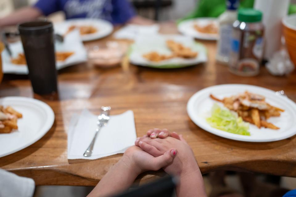 Fine Palu, 7, and her brother “Bubba,” 4, hold hands while the family prays before dinner at their home in Eagle Mountain on Tuesday, Nov. 28, 2023. | Spenser Heaps, Deseret News