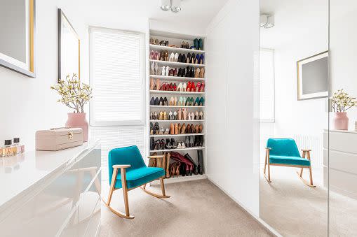 dreamy feminine wardrobe with white furniture, big mirror, shoe closet, beige carpet, blue retro armchair and pastel pink accessories