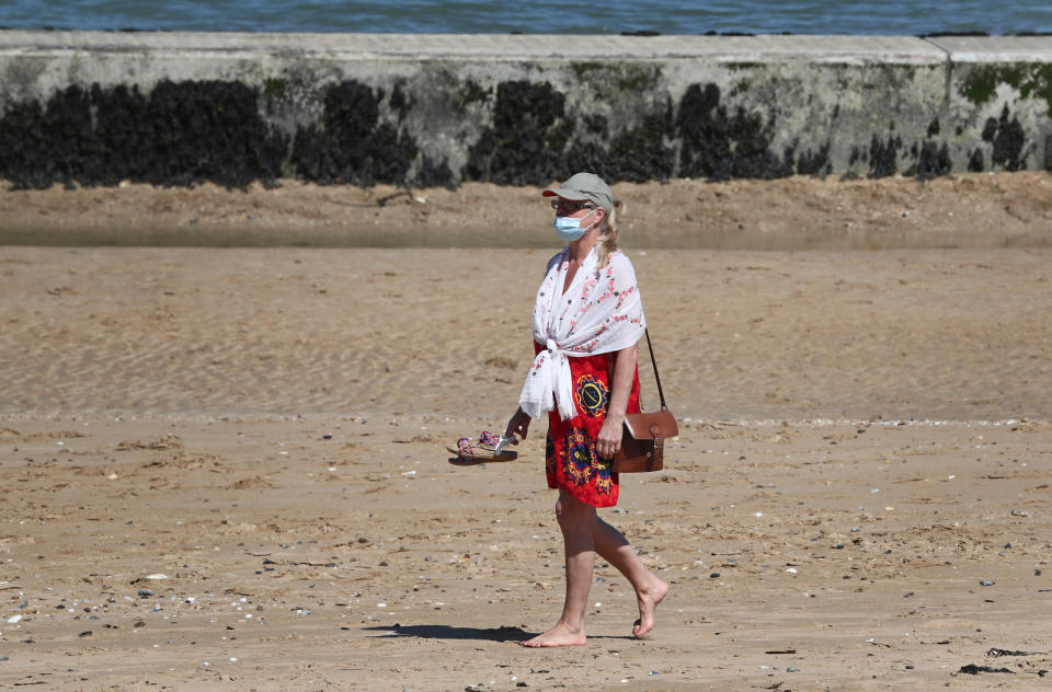 A lady in a mask walks on the beach in Margate, Kent, as the UK continues in lockdown to help curb the spread of the coronavirus.