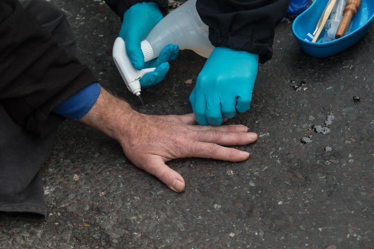 ESSEX, ENGLAND - OCTOBER 13: Police spray solvent onto a hand that is superglued to the road as they arrest activists from Insulate Britain block a junction near the Dartford Crossing on October 13, 2021 in Thurrock, England.(Photo by Guy Smallman/Getty Images)