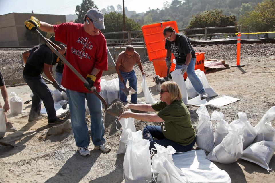 Mark and Barbara Albanese fill sand bags to protect their home from the possible flooding ahead of an expected rain storm in Azusa,Calif. on Tuesday, Feb 25, 2014. In anticipation of the first substantial winter storm system in drought-stricken California, residents of foothill communities picked up sandbags at fire stations and city yards to protect their homes on Tuesday. (AP Photo/Nick Ut )
