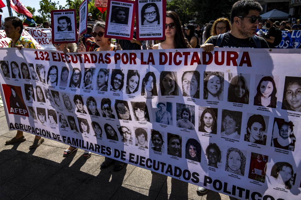 Protesters hold a banner with pictures of people killed during the military dictatorship of Augusto Pinochet's dictatorship in a march marking Human Rights Day, in Santiago, Chile, Saturday, Dec. 10, 2022. (AP Photo/Esteban Felix)