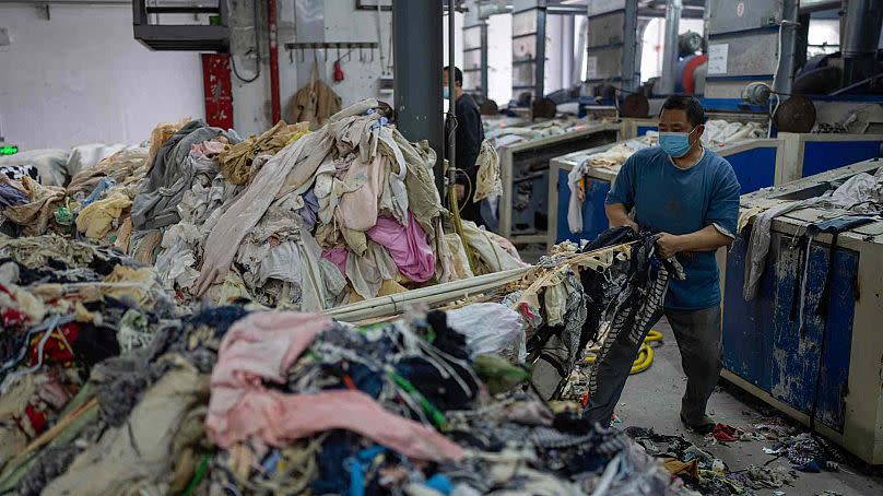 Un ouvrier introduit des textiles usagés dans une machine à broyer à la Wenzhou Tiancheng Textile Company, l'une des plus grandes usines de recyclage de coton de Chine.