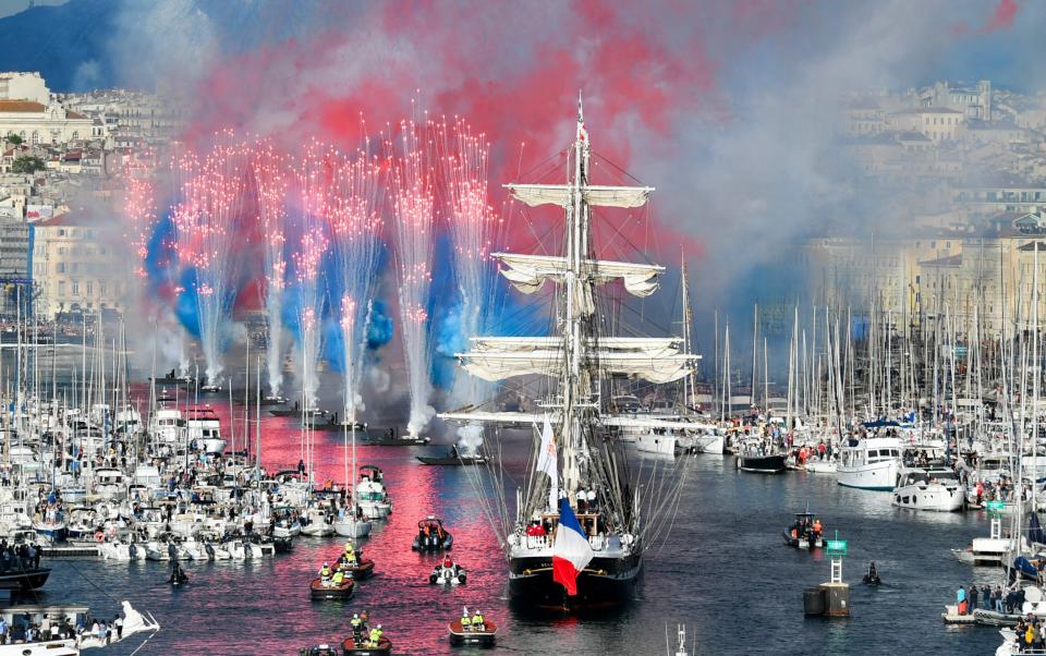 A flotilla in Marseille harbour with fireworks and smoke bombs going off in tricolor colours