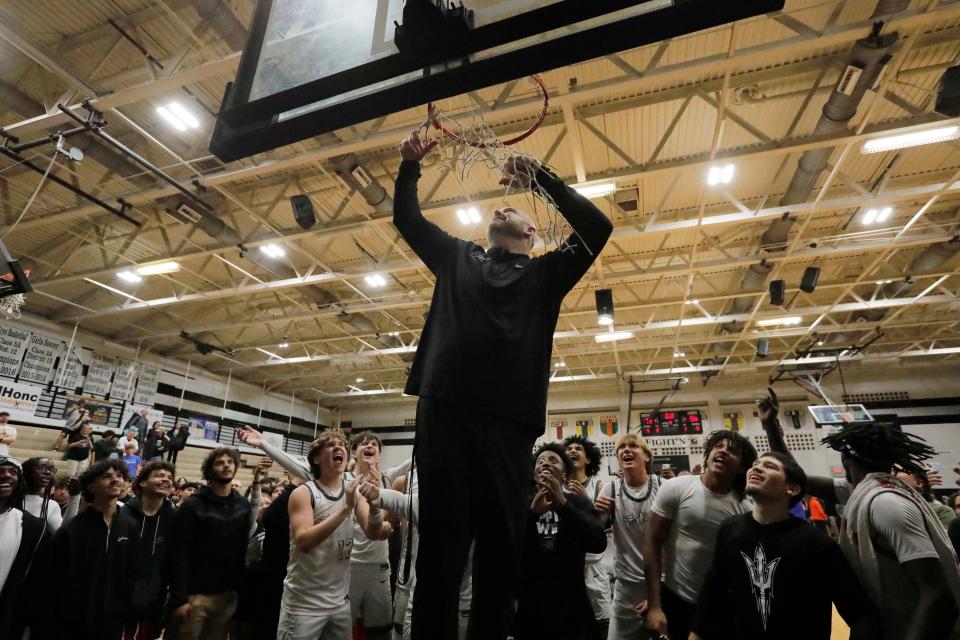Mariner head coach Ryan Hercek cuts the net after his team defeated Seminole High School with a final score of 73-56 Friday, February 23, 2024. The team will move on to the state final four tournament.