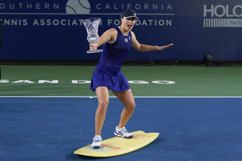 Iga Swiatek, of Poland, poses with the trophy on a surfboard after defeating Donna Vekic, of Croatia, to win the San Diego Open tennis tournament, Sunday, Oct. 16, 2022, in San Diego. (AP Photo/Gregory Bull)