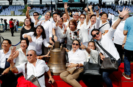 Filipinos pose next to a Balangiga bell after its arrival at Villamor Air Base in Pasay, Metro Manila, Philippines December 11, 2018. REUTERS/Erik De Castro