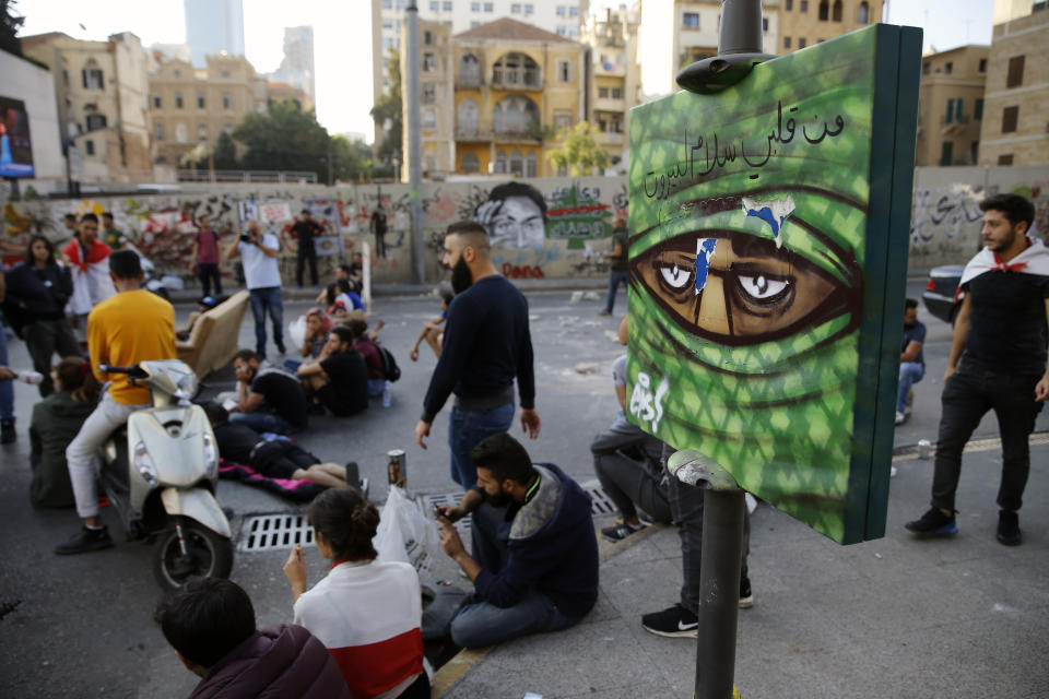 Anti-government protesters block a main highway in Beirut, Lebanon, Wednesday, Nov. 13, 2019. A local official for a Lebanese political party was shot dead by soldiers trying to open a road closed by protesters in southern Beirut late Tuesday, the army reported, marking the first death in 27 days of nationwide protests. The Arabic writing on the graffiti reads: "Regards from my heart to Beirut." (AP Photo/Bilal Hussein)