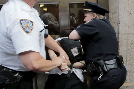 A protester is detained by New York Police Department officers during a march for Eric Garner's anniversary who was killed one year ago by police in New York July 17, 2015. REUTERS/Eduardo Munoz