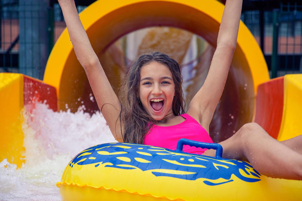 A young girl rides a yellow inner tube in a water park.