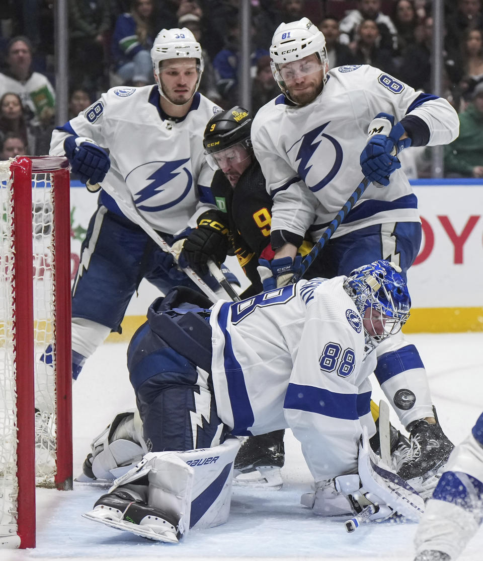 Tampa Bay Lightning goalie Andrei Vasilevskiy (88) stops Vancouver Canucks' J.T. Miller (9) as Tampa Bay's Erik Cernak (81) and Brandon Hagel (38) defend during the third period of an NHL hockey game in Vancouver, B.C., on Tuesday, Dec. 12, 2023. (Darryl Dyck/The Canadian Press via AP)