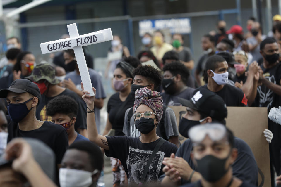 Eine Demonstrantin hält während einer Protestkundgebung gegen Rassismus und Polizeigewalt ein Kreuz, auf dem der Name George Floyd geschrieben ist, hoch. Foto: Silvia Izquierdo / AP / dpa