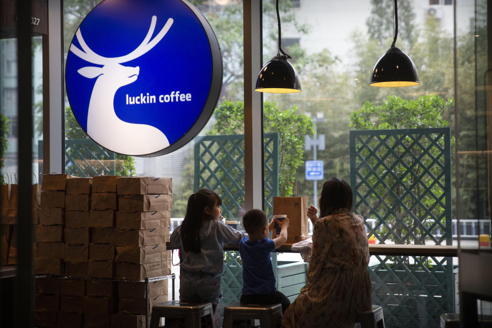 Customers sit inside a Luckin Coffee shop at a shopping center in Beijing, Saturday, May 18, 2019. Shares of Luckin Coffee, a fast-growing rival to Starbucks in China, rose 20% in their U.S. stock market debut Friday. (AP Photo/Mark Schiefelbein)