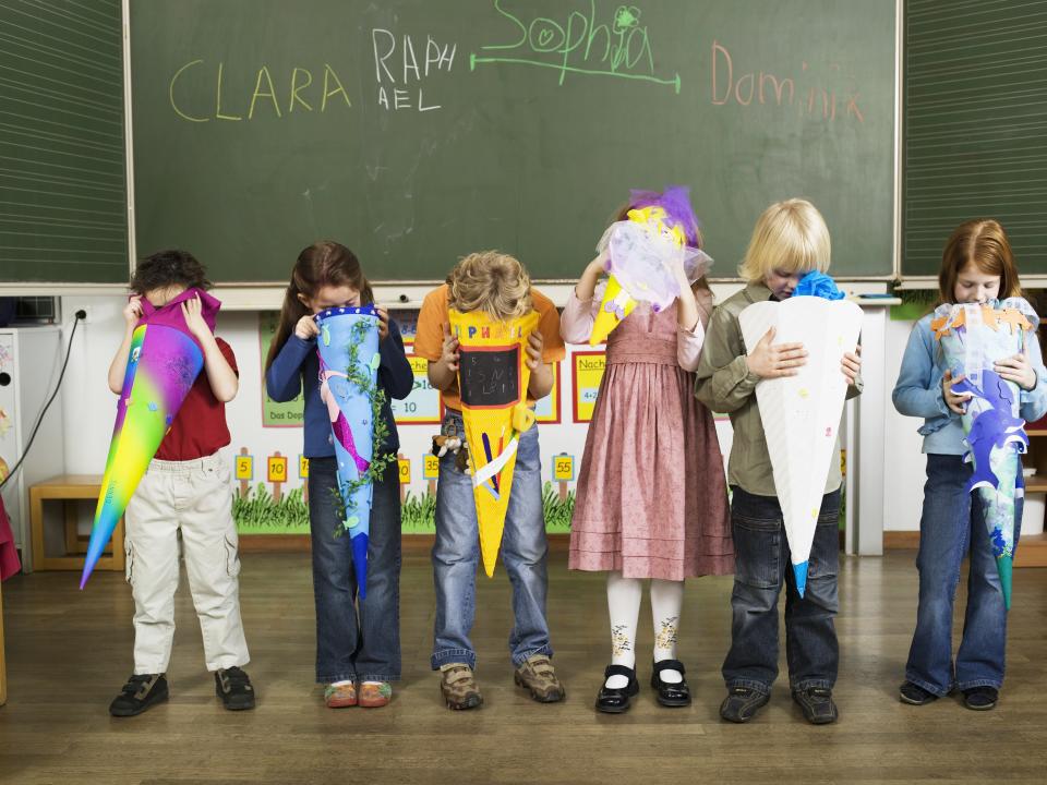 Children (4-7) standing in front of blackboard looking in to school cones