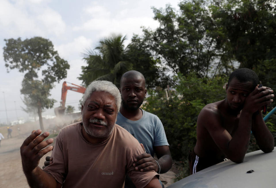 <p>Carlos Augusto (L), who has lived in the Vila Autodromo slum for 20 years, reacts as his house is being demolished after he moved to one of the twenty houses built for the residents who refused to leave the community, in Rio de Janeiro, Brazil, August 2, 2016. (REUTERS/Ricardo Moraes)</p>