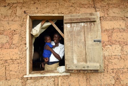 Mariatu Sesay, 15, carries her daughter as she looks out the window in a countryside village of Sierra Leone