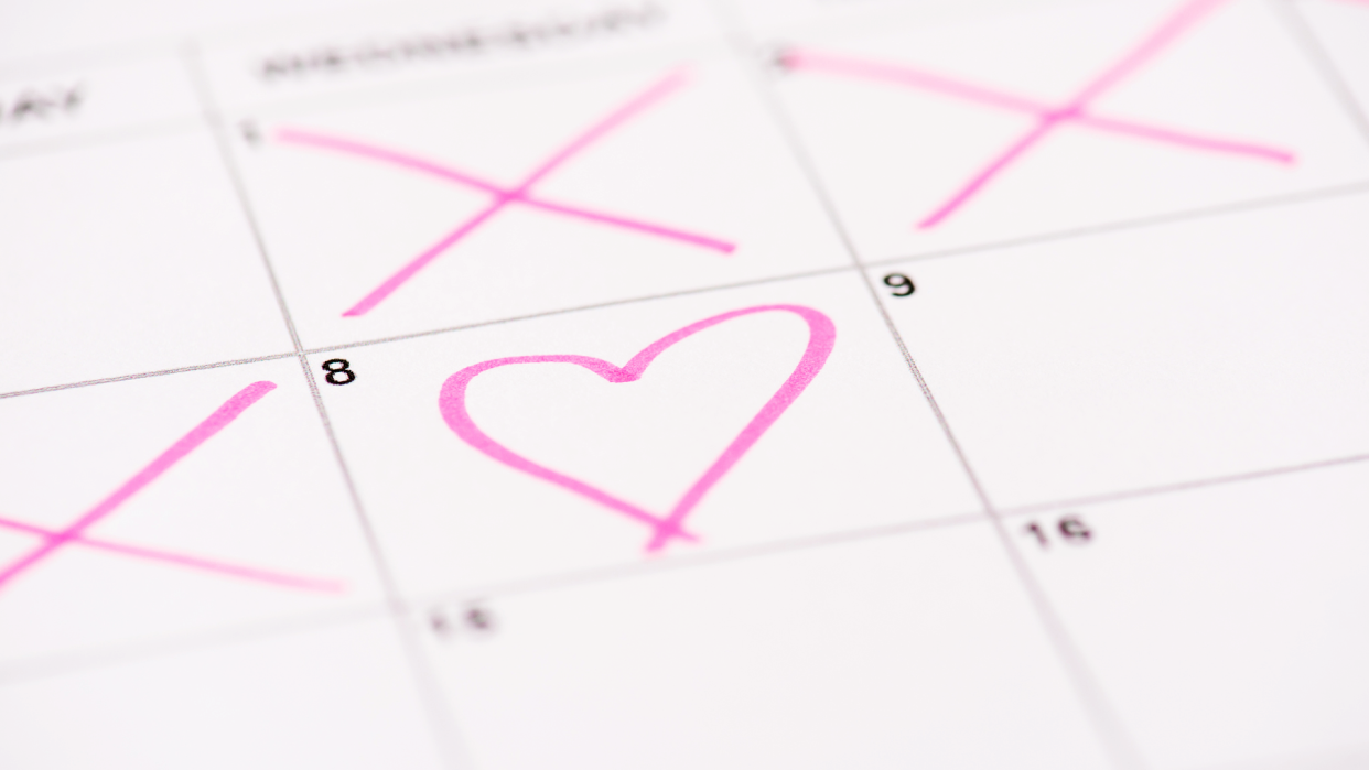 Calendar with a pink heart on one day and other days crossed out depicting natural family planning.