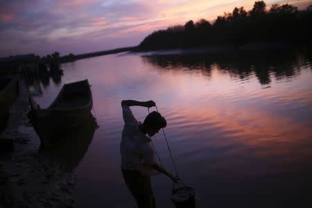 A Rohingya man pulls water out of river at the port near the border between Bangladesh and Myanmar in Maungdaw town in northern Rakhine State November 11, 2014. REUTERS/Minzayar