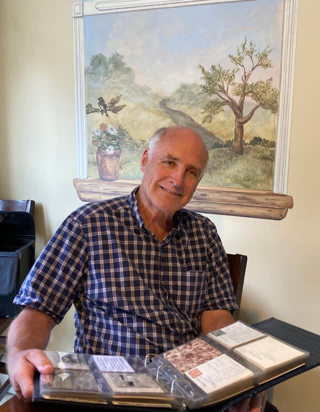 Brian Bursey holds one of the 50 volumes that store his postcard collection, which consists of as many as 5000 postcards. He says he started collecting 15 years ago and is still adding to it.