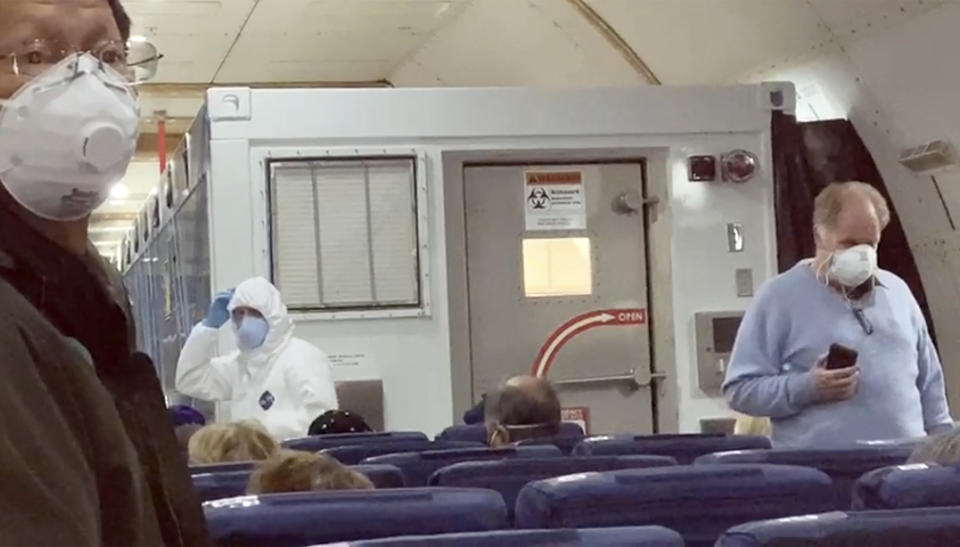 In this image from a video taken on Monday, Feb. 17, 2020, U.S. passengers who evacuated off the quarantined cruise ship the Diamond Princess, wait for the takeoff of a Kalitta Air plane bound for the U.S., at Haneda airport in Tokyo.(Cheryl and Paul Molesky via AP)