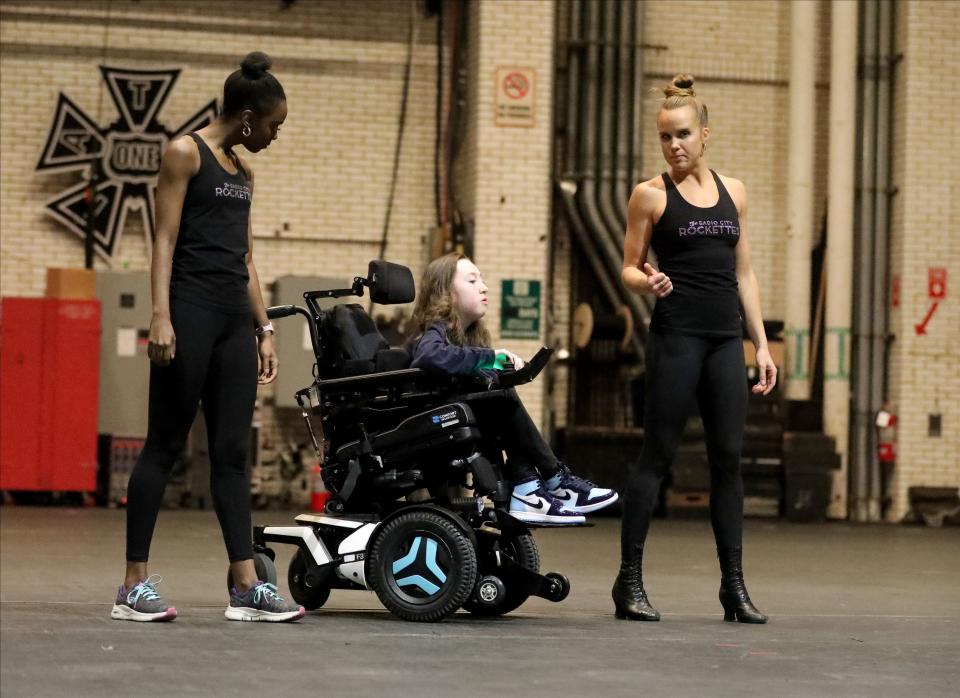 Avery Roberts, 15, a freshman at Clarkstown South High School is escorted on the Radio City Music Hall stage by Rockettes Latarika Pierce and Katelyn Gaffney, during a rehearsal for the Garden of Dreams Talent Show in New York, April 11, 2023. Roberts, sponsored by the Make-A-Wish Hudson Valley, danced to the song "Rescue".