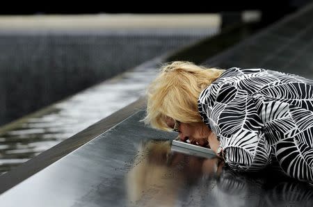 Paola Braut, of Belgium, kisses a photograph of her son Patrice along the edge of the North Pool during memorial observances held at the site of the World Trade Center in New York, September 11, 2014. REUTERS/Justin Lane/POOL