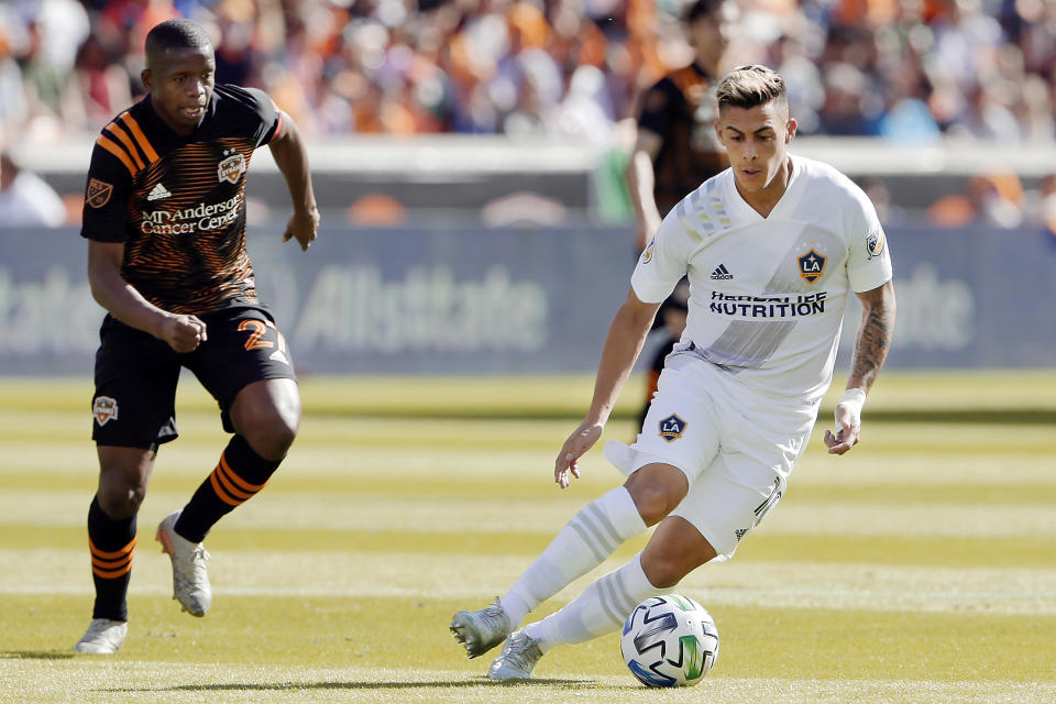 Los Angeles Galaxy forward Cristian Pavón, right, moves the ball in front of Houston Dynamo midfielder Boniek García (27) during the first half of an MLS soccer match Saturday, Feb. 29, 2020, in Houston. (AP Photo/Michael Wyke)