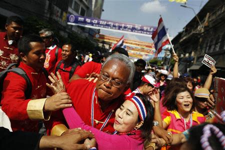 Protest leader Suthep Thaugsuban wearing red for the Chinese New Year is hugged by an anti-government protester during a march through Chinatown in Bangkok February 1, 2014. REUTERS/Damir Sagolj