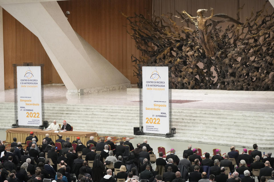 Pope Francis, sitting at left at the table, listens to Cardinal Marc Ouellet's opening address as he attends the opening of a 3-day Symposium on Vocations in the Paul VI hall at the Vatican, Thursday, Feb. 17, 2022. (AP Photo/Gregorio Borgia)