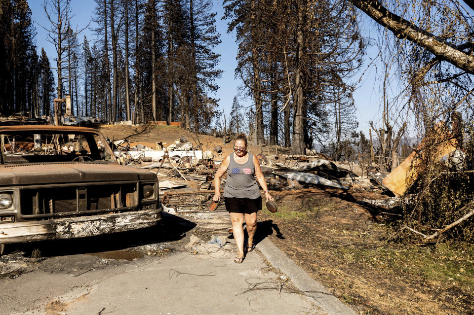 Kimberly Price leaves food for cats at the home of her boyfriend, volunteer firefighter John Hunter, on Sunday, Sept. 5, 2021, in the Greenville community of Plumas County, Calif. Hunter, whose home burned during the Dixie Fire in August, received a motorhome from EmergencyRV.org earlier in the day. (AP Photo/Noah Berger)