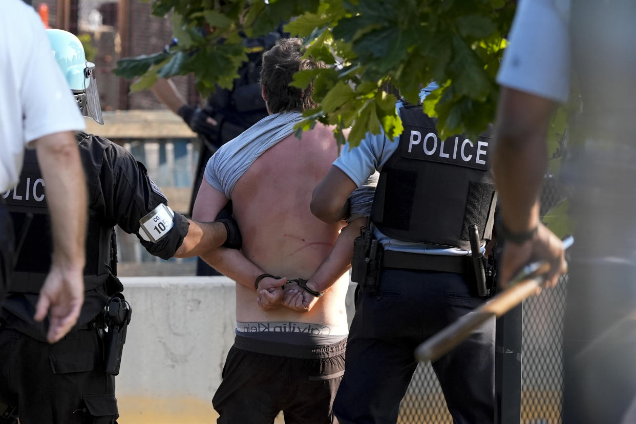 Police take a handcuffed, barebacked protester into custody outside the Democratic National Convention in Chicago on Monday. 