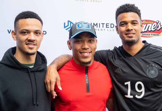 <p>Maximilian Haupt/picture alliance/Getty</p> Amon-Ra St. Brown between his brothers Osiris and Equanimeous after being selected in the NFL draft.