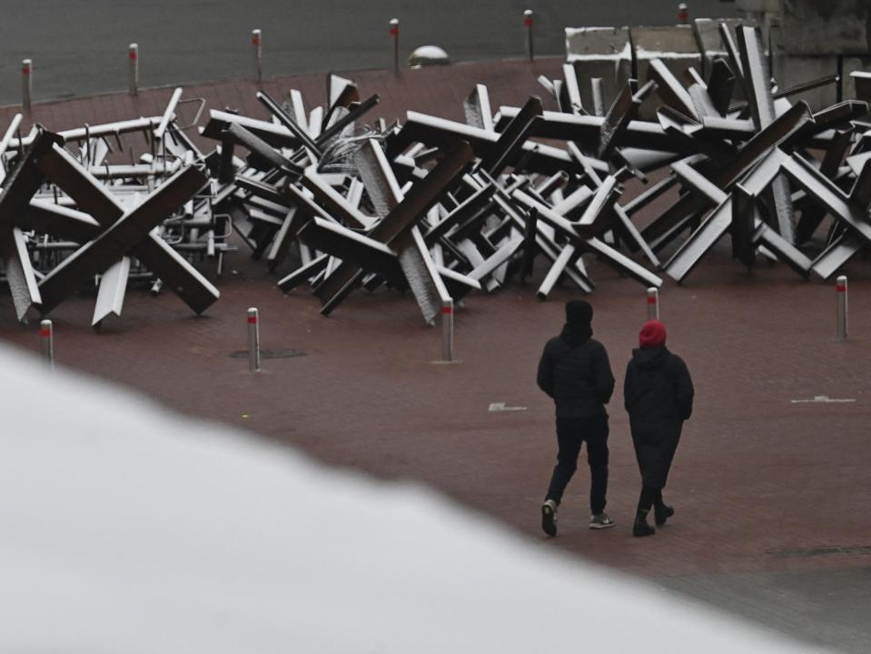 Pedestrians walk past anti-tank constructions covered with snow in Kyiv (AFP/Getty)