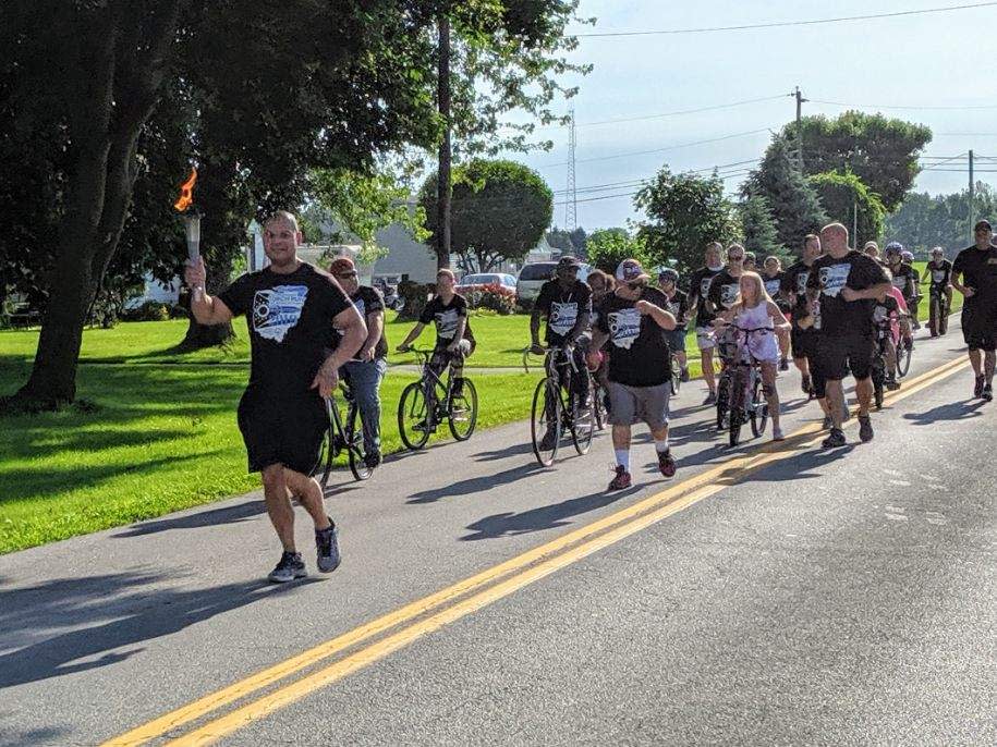 Fremont Police officer Michael Kennedy leads a group of police officers and people from Sandusky County Developmental Disabilities through the streets of Fremont Thursday for one of the annual Law Enforcement Torch Runs for the Special Olympics.