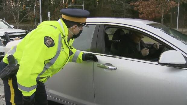 An RCMP officer talks to a driver at an impaired-driving checkpoint in December 2020. Premier John Horgan says policing of B.C.'s impending travel restrictions will involve similar checkpoints, which has raised concerns from the B.C. Civil Liberties Association. (CBC - image credit)